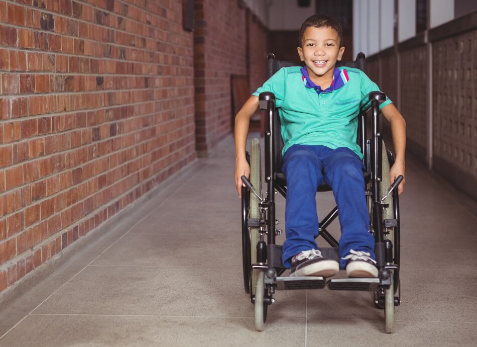 Young boy in wheelchair outside on path