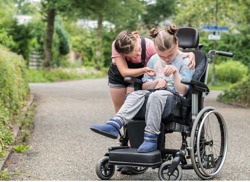 Girl with a disability in wheelchair outdoors with friend