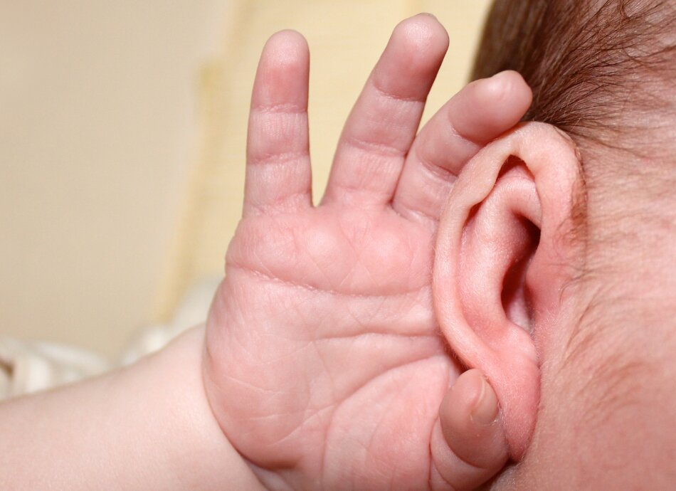 Baby's hand cupping its right ear