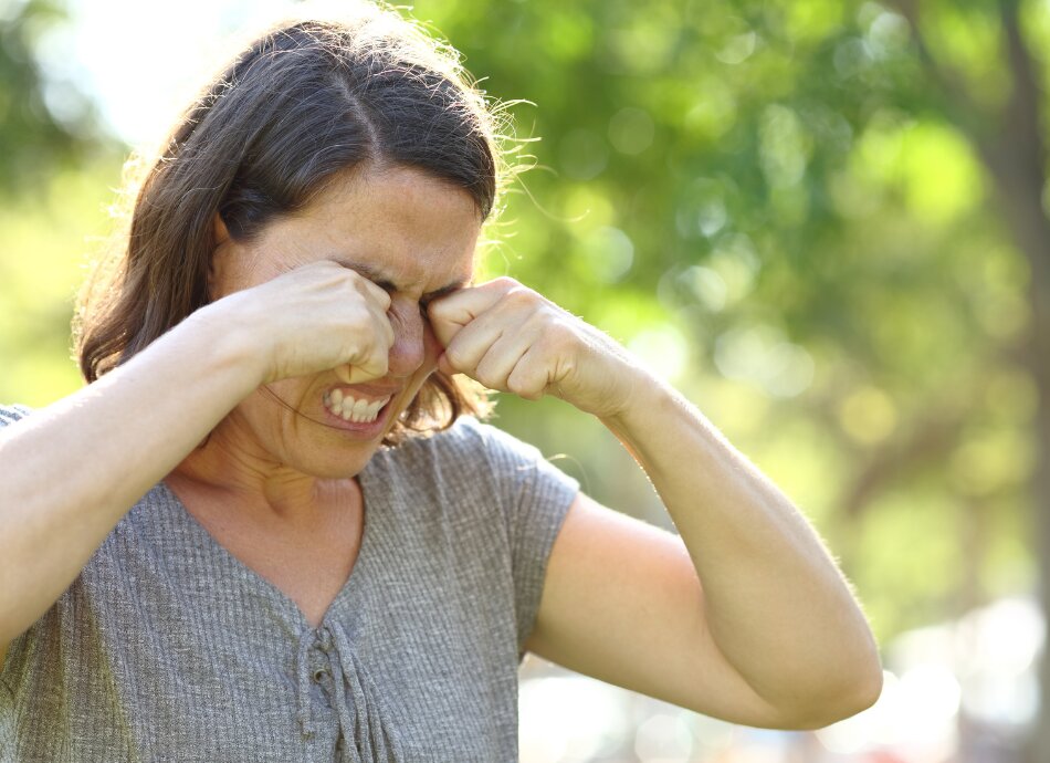 Woman outdoors rubbing itchy, sore eyes