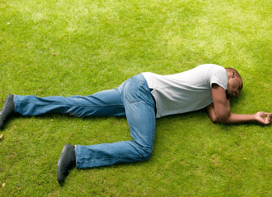 Man lies on grass in recovery position