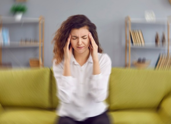 Woman sitting on couch feeling dizzy