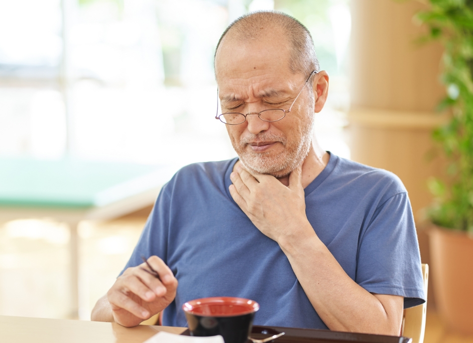 Man with swallowing problems holding throat 