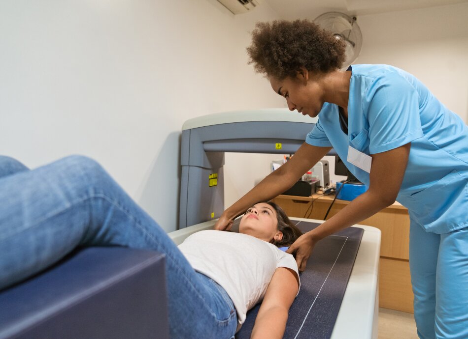 Healthcare professional guides woman lying on bench having bone density or DEXA scan