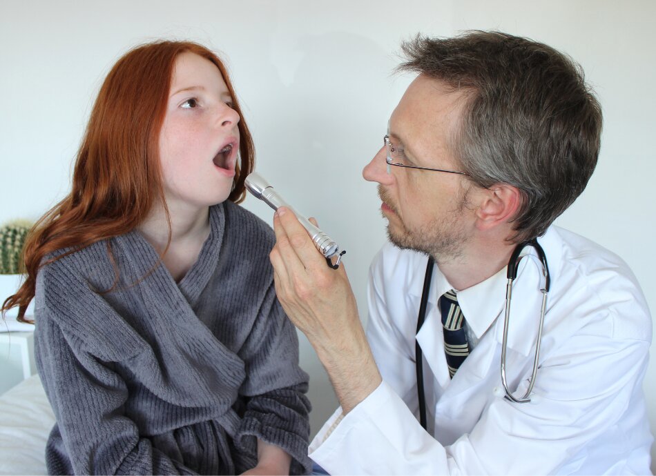 Doctor looking in girls throat with torch