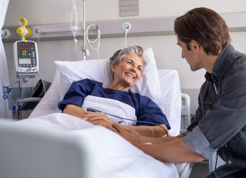 Older woman in hospital bed smiles at son