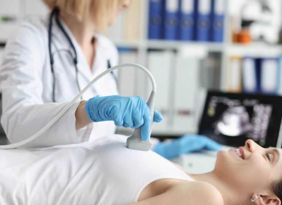 Woman lying on bench having breast ultrasound of left breast