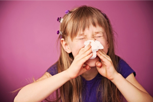 Girl blowing her nose into a tissue