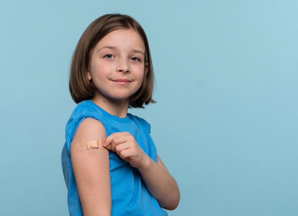 Girl shows bandaid on left arm