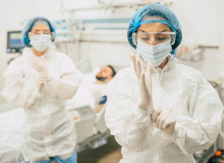 Hospital staff in PPE gear with man in background