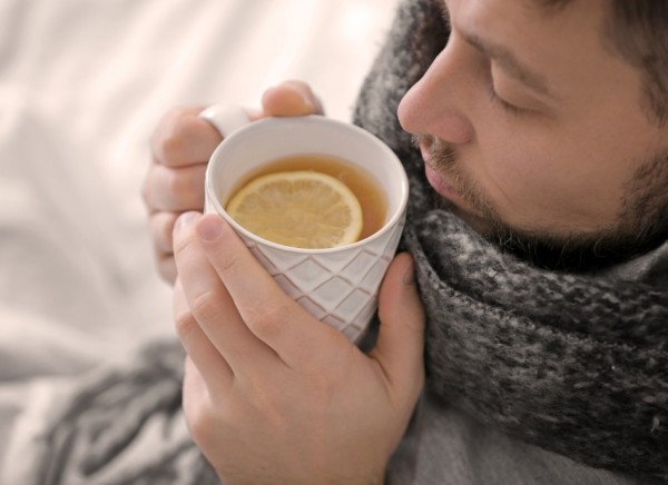 Unwell man drinking hot honey and lemon