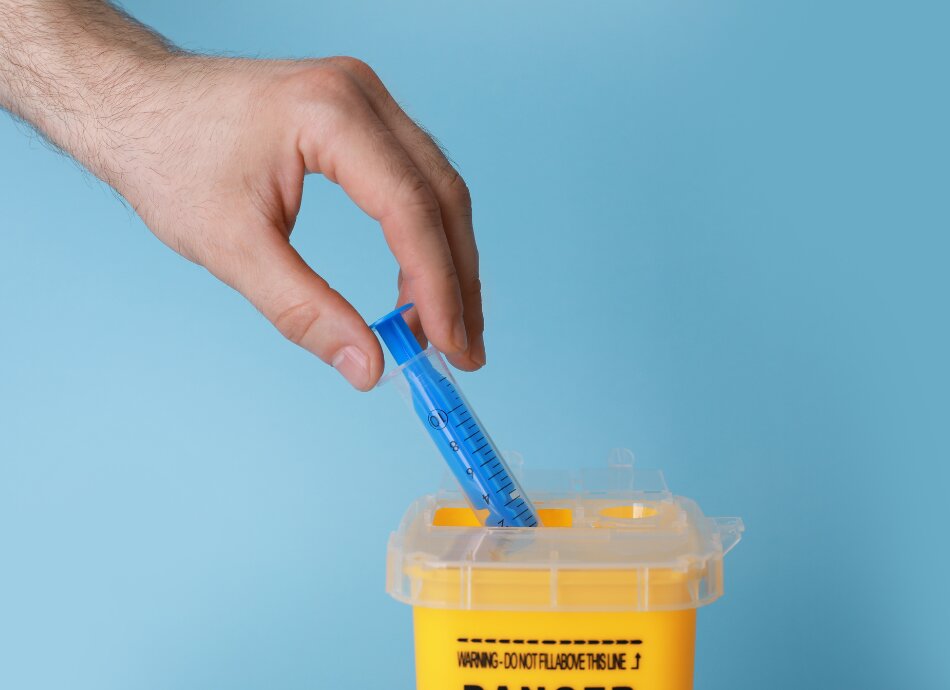 Syringe being put into sharps container