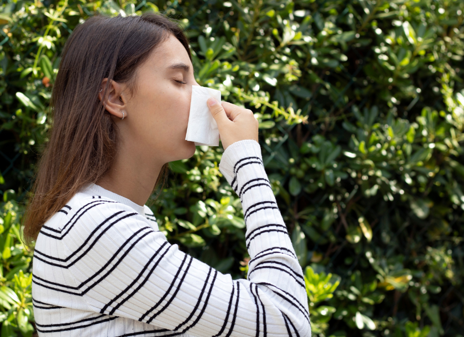 Woman outdoors blowing her nose into a tissue