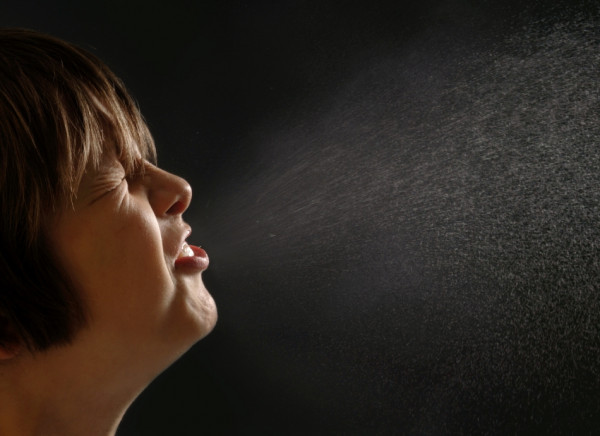 Woman sneezing and spreading droplets of saliva