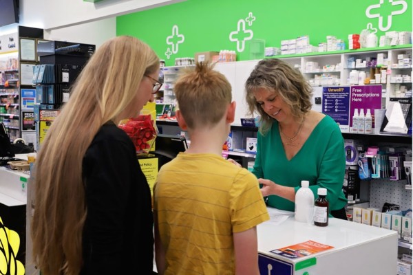 Woman and son talking to pharmacist over the counter