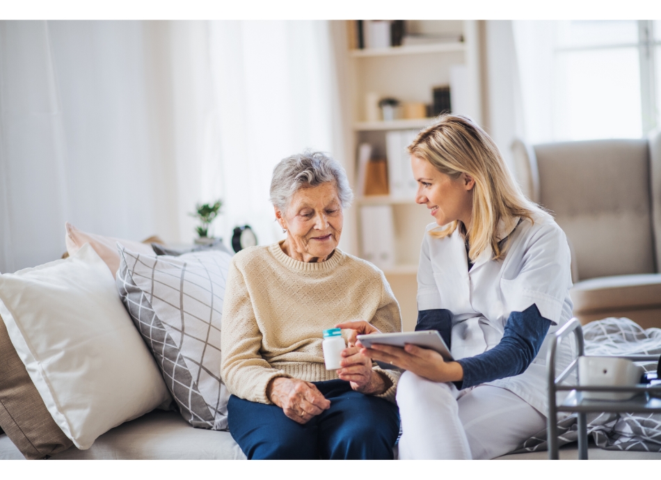 Healthcare worker advising older woman at home on taking medicine Canva 950x690