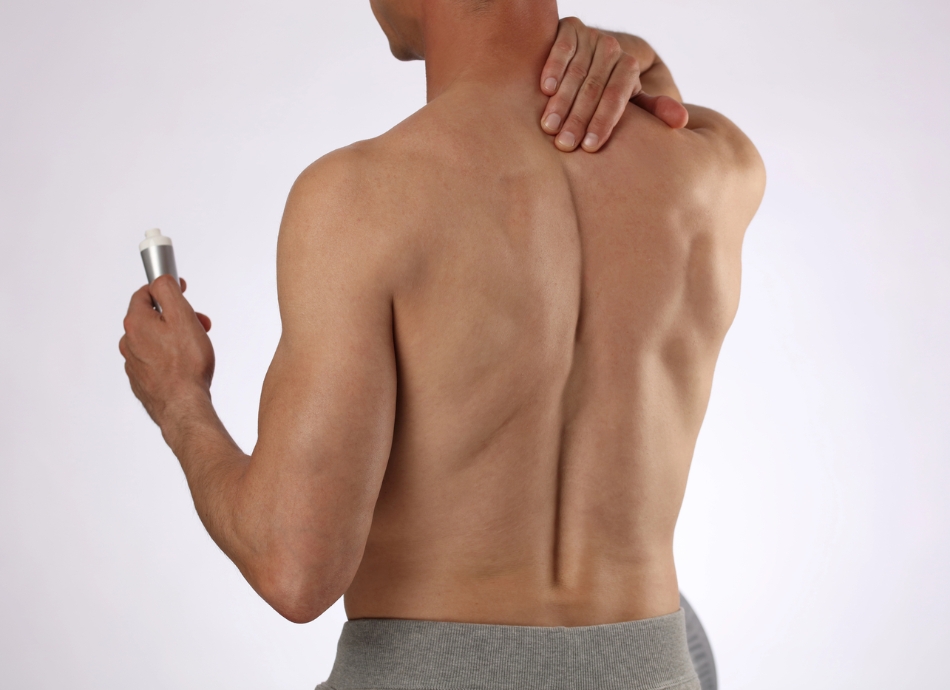 Man rubbing pain relief cream into shoulder 