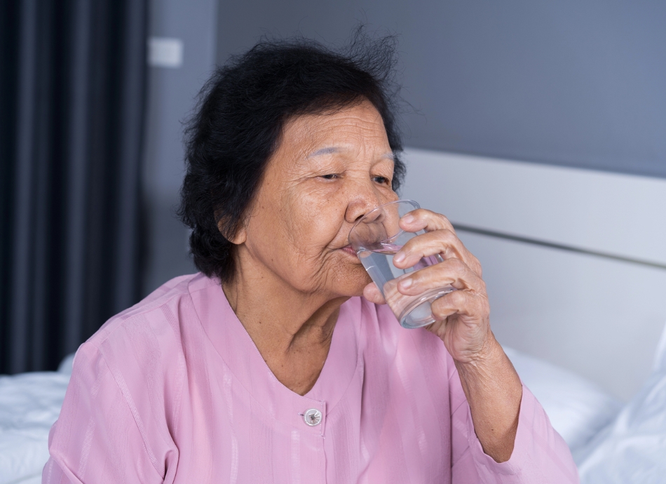 Older woman drinking water at home 