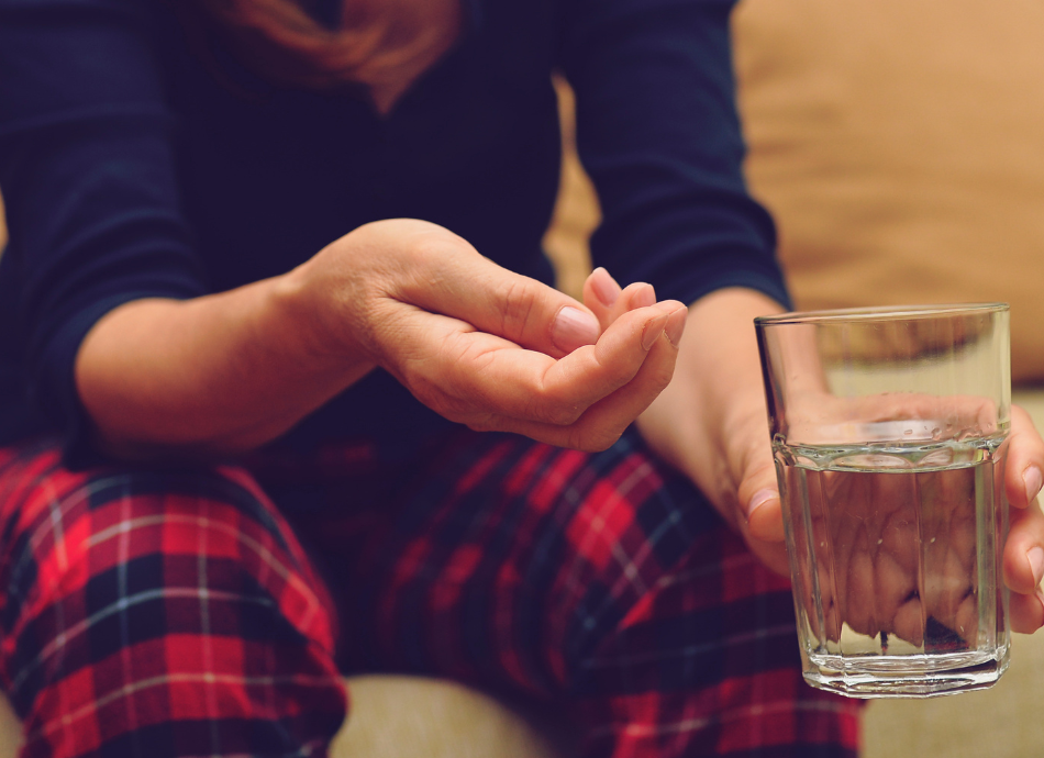 Person about to take pill with glass of water 