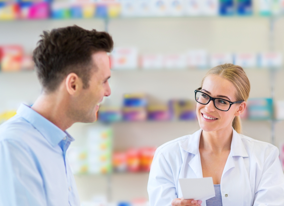 Pharmacist holding a prescription talking to male patient Canva 950x690