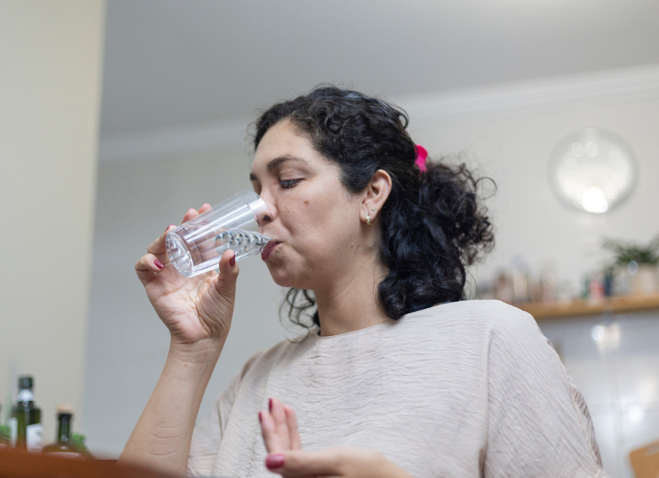 Woman swallowing pill with water