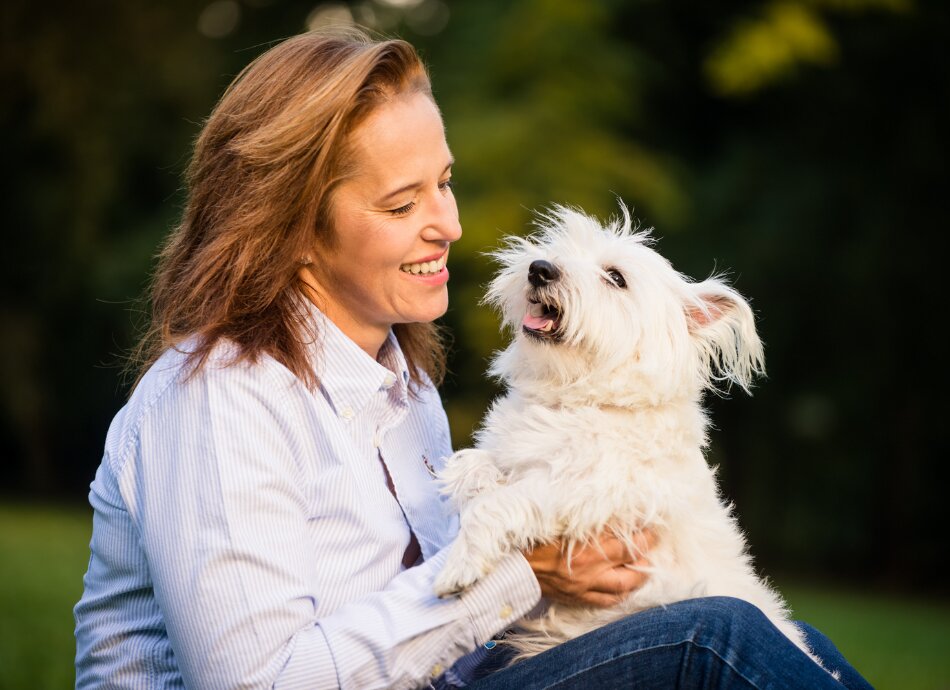 Woman sites outdoors with small white dog