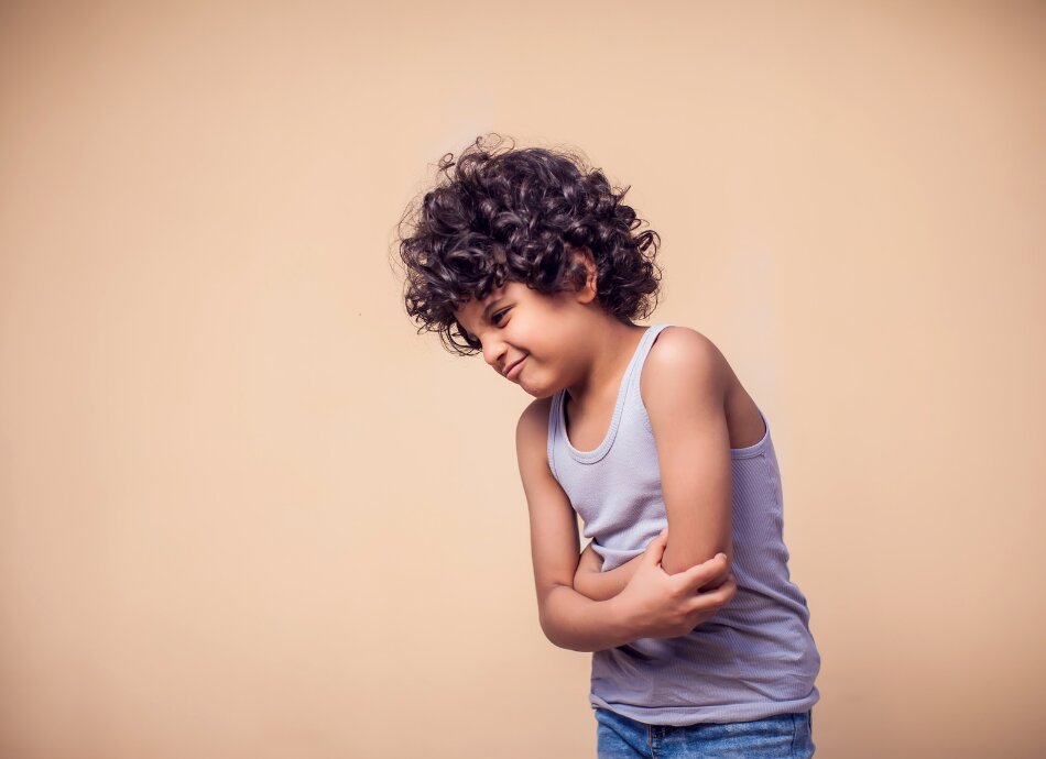 Young boy holds stomach feeling sick