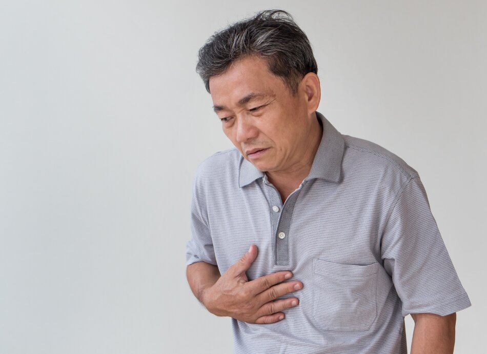 Male clutches chest with heartburn pain