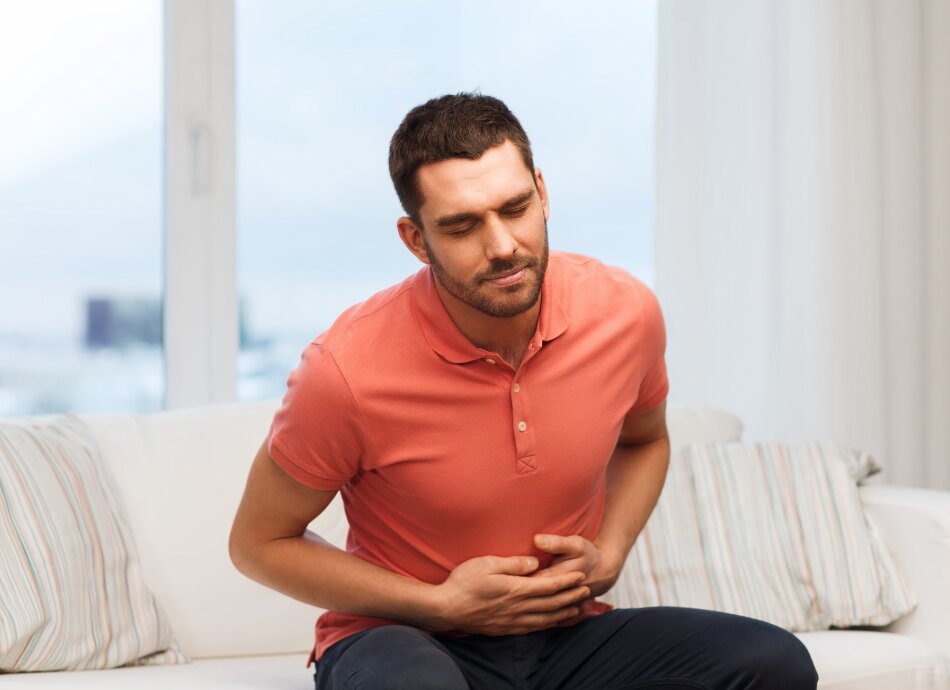 Man clutching sore gut with eyes closed 