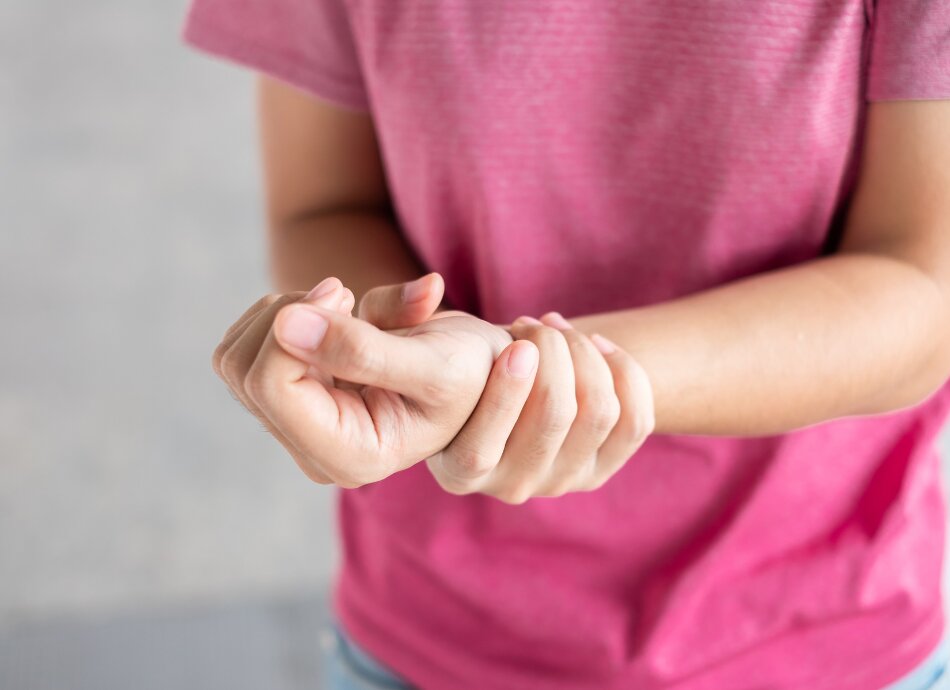 Woman in pink tee-shirt holding painful wrist or hand