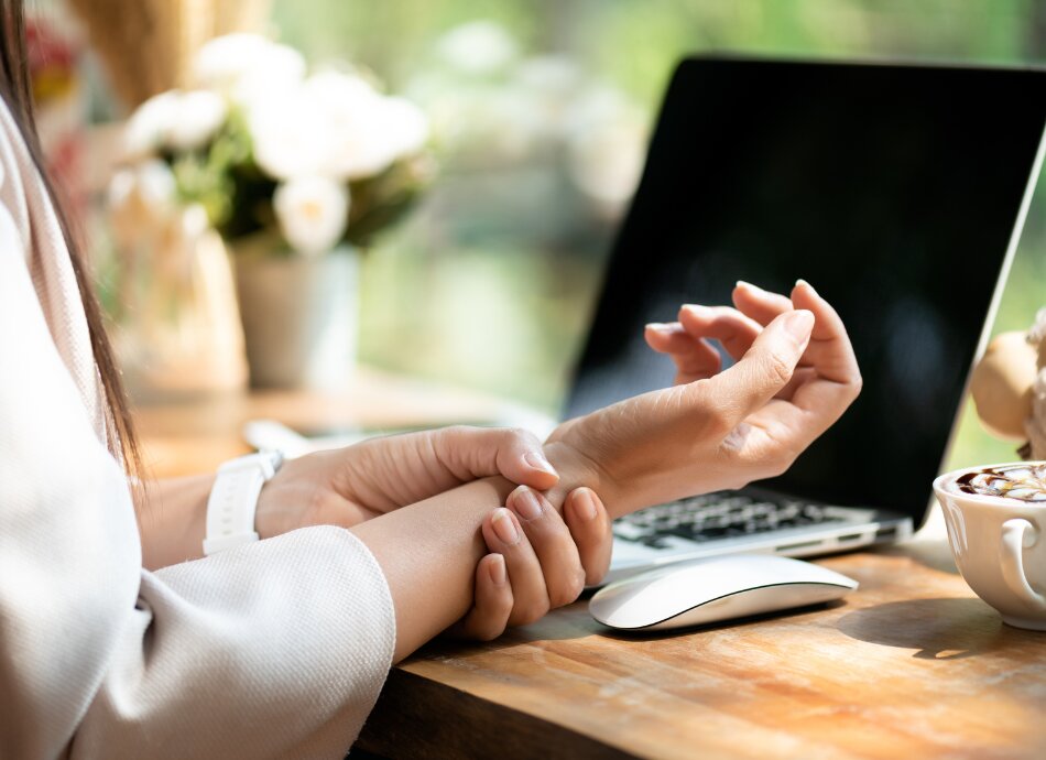 Woman holding wrist sore from typing or computer work