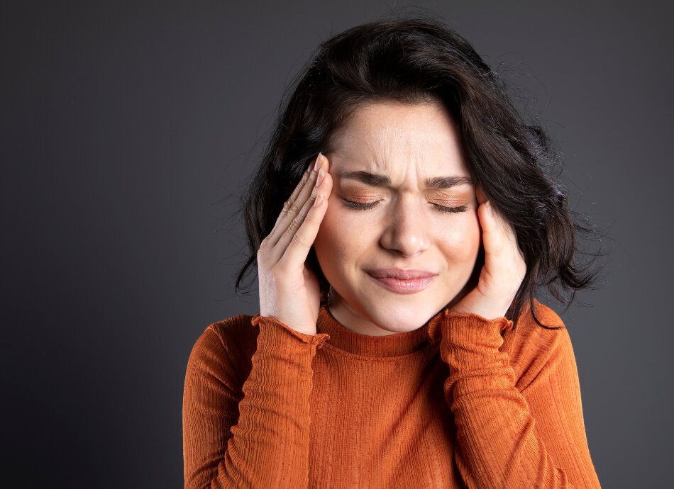 Young woman closes eyes with headache pain