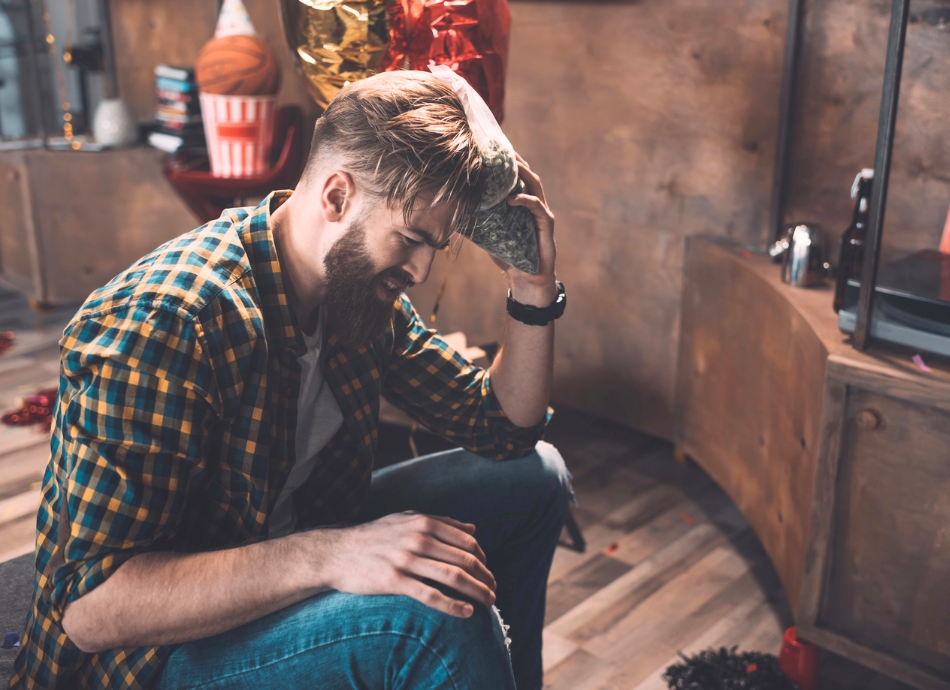 Young man with sore head the morning after a party 