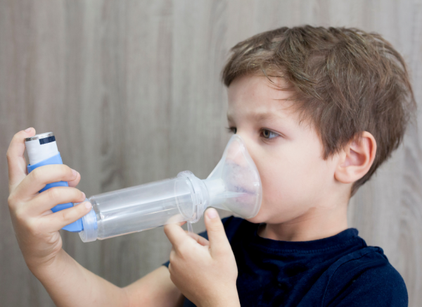 Boy using aerosol inhaler with spacer