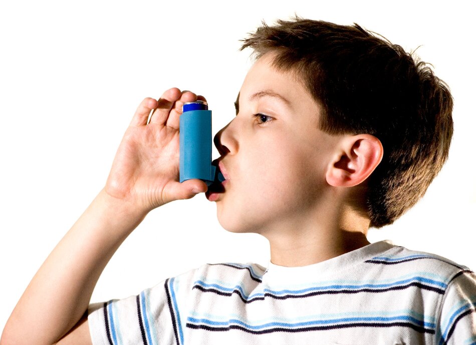 Young boy in striped tee-shirt uses inhaler for asthma