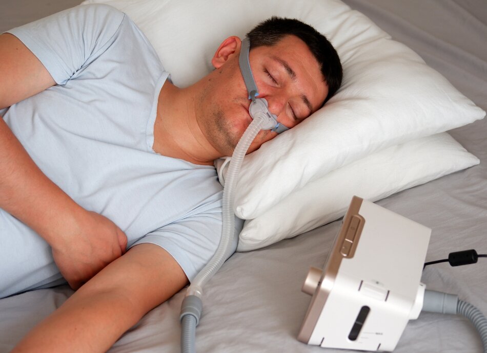 Man using CPAP mask while asleep in bed