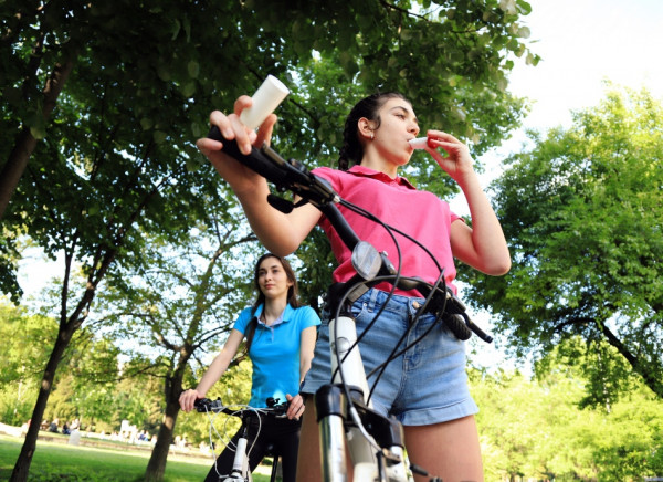 Young woman using an asthma inhaler during a bike ride