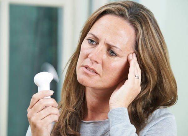 Woman using a handheld fan to help with hot flushes