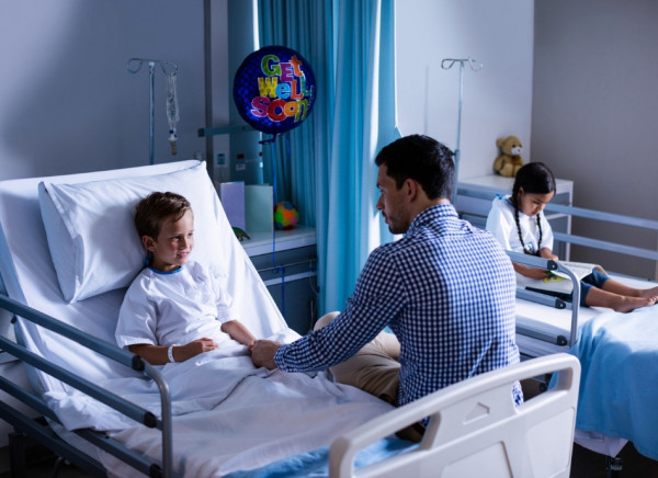 Boy sitting in hospital bed talking to parent