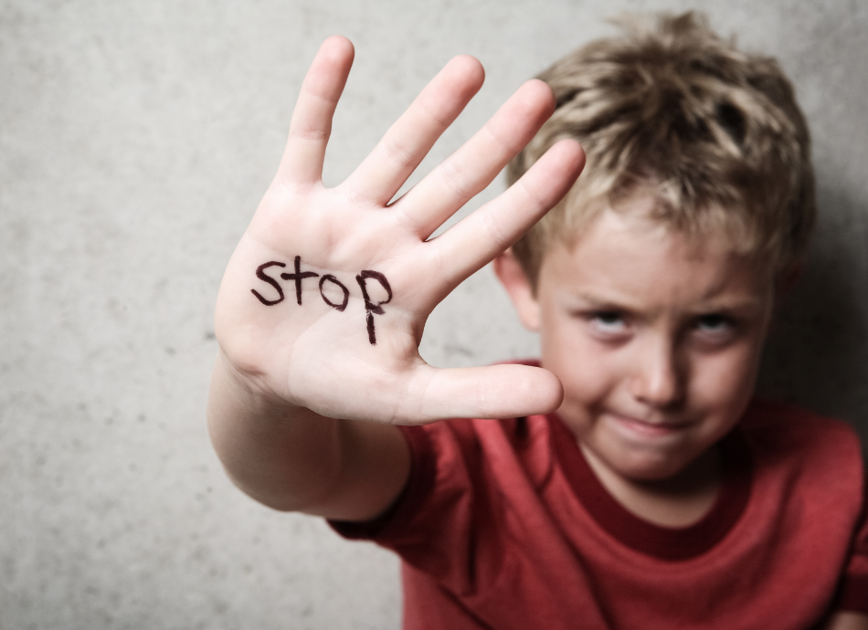 Boy holding up his hand with word 'stop' on it