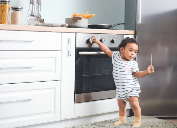 Toddler touching the oven knobs in the kitchen
