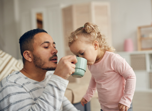 Man helping small girl drink from a cup