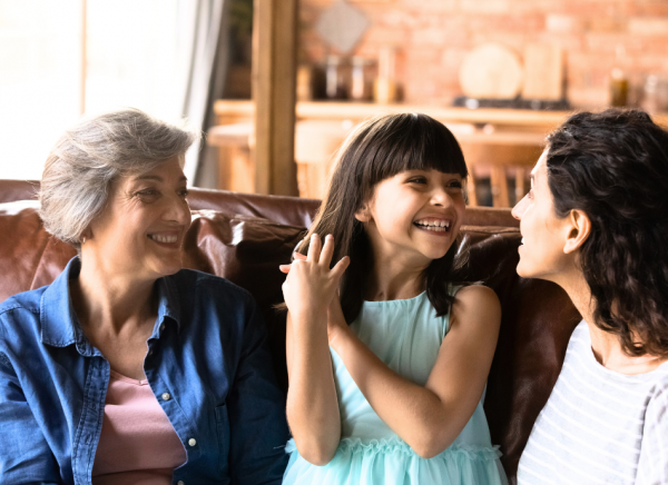 Family on couch with mother and daughter making eye contact smiling and  and talking 
