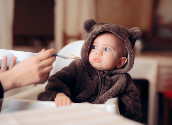 Toddler in highchair reluctant to eat food offered on spoon