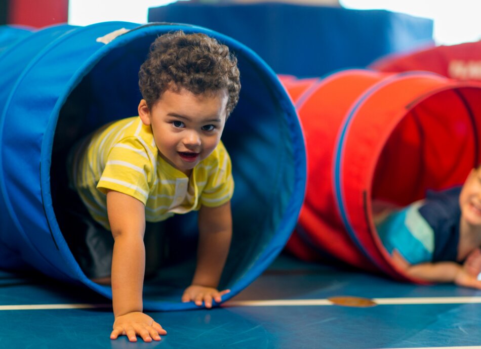 2 toddlers playing in a pop-up tunnel