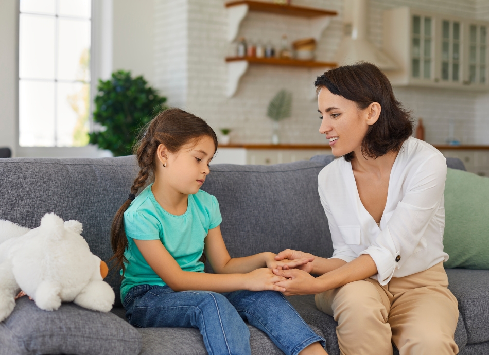 Woman talking to child with teddy on the couch 