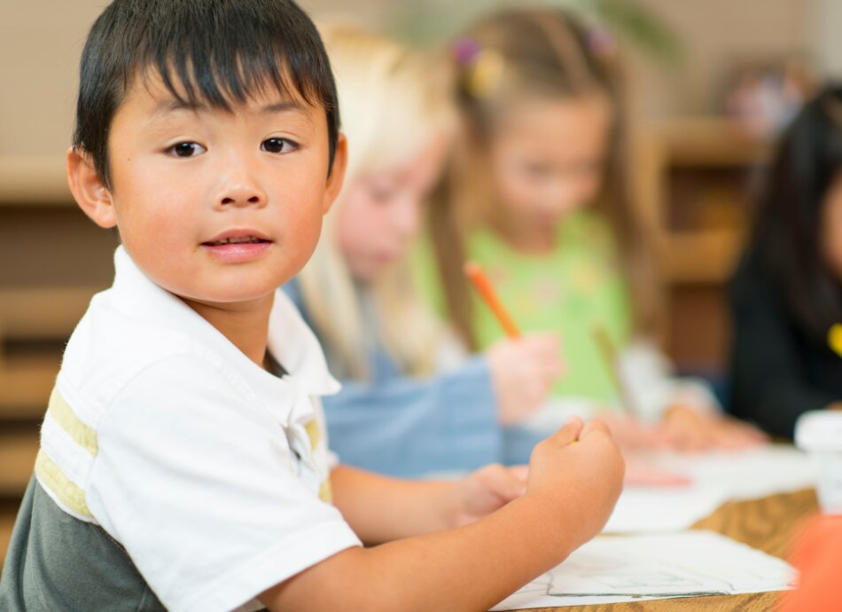 Preschoolers sitting at a table writing