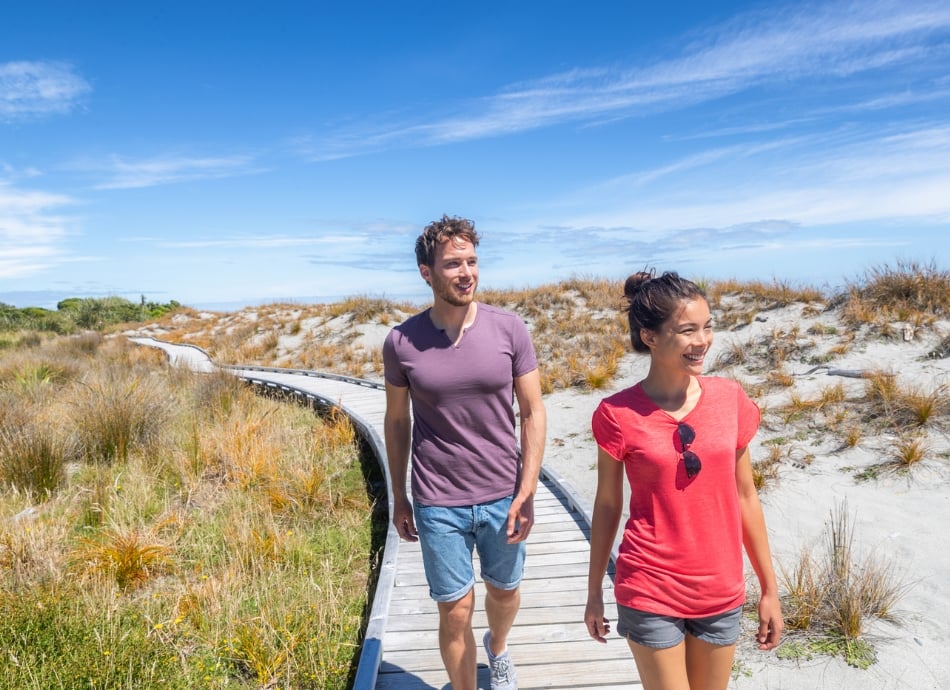 Couple walking on NZ beach 