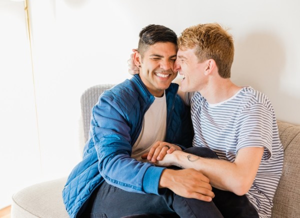 Male couple cuddling on couch