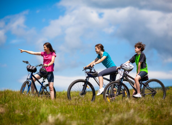 Family of three riding bikes on hillside